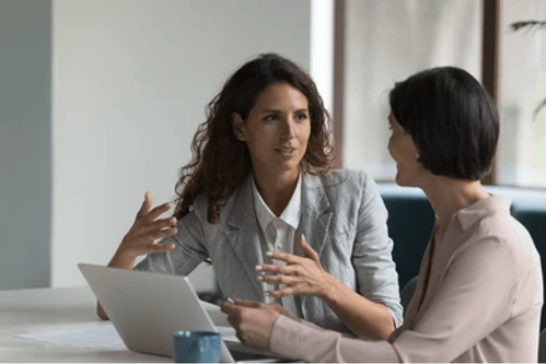 Two colleagues engaged in one-on-one conversation, reflecting healthy interpersonal dynamics and trust in a team setting